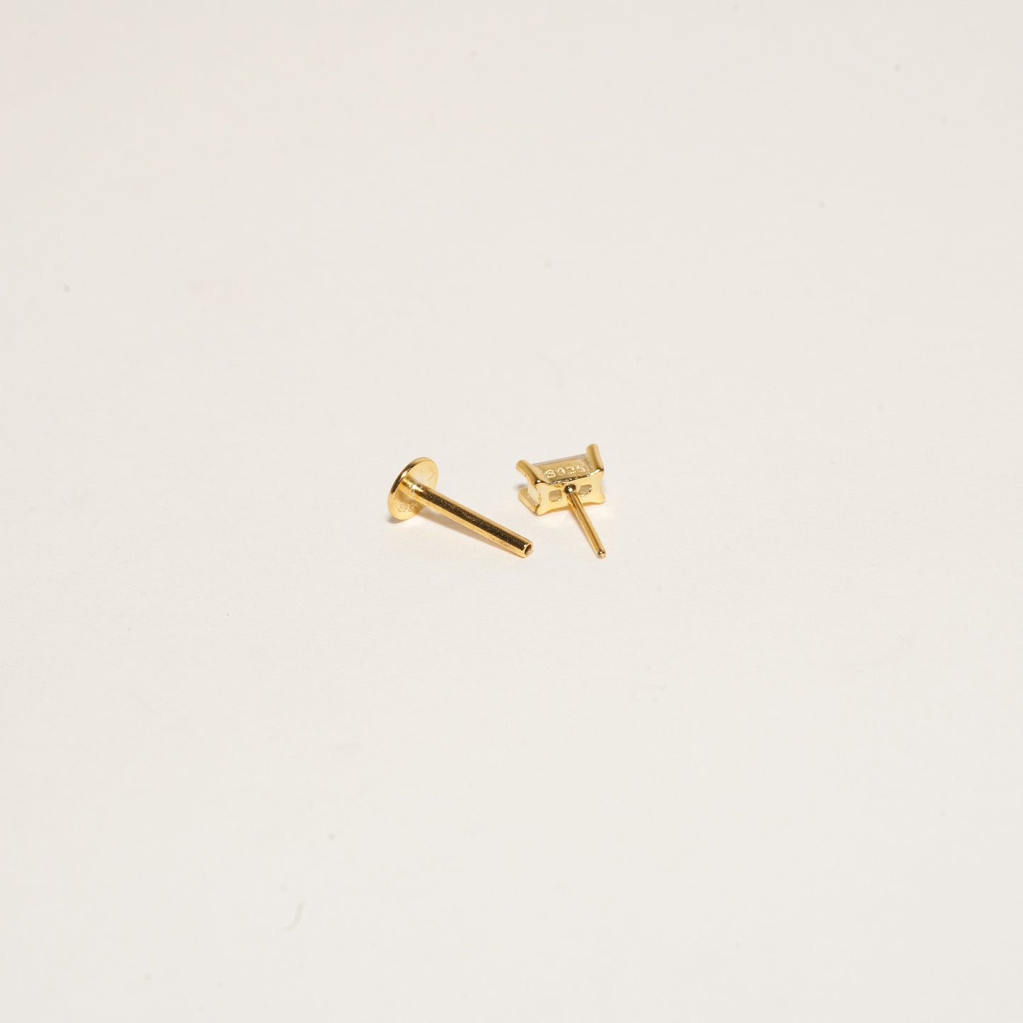 Gold stud earrings on a light beige background