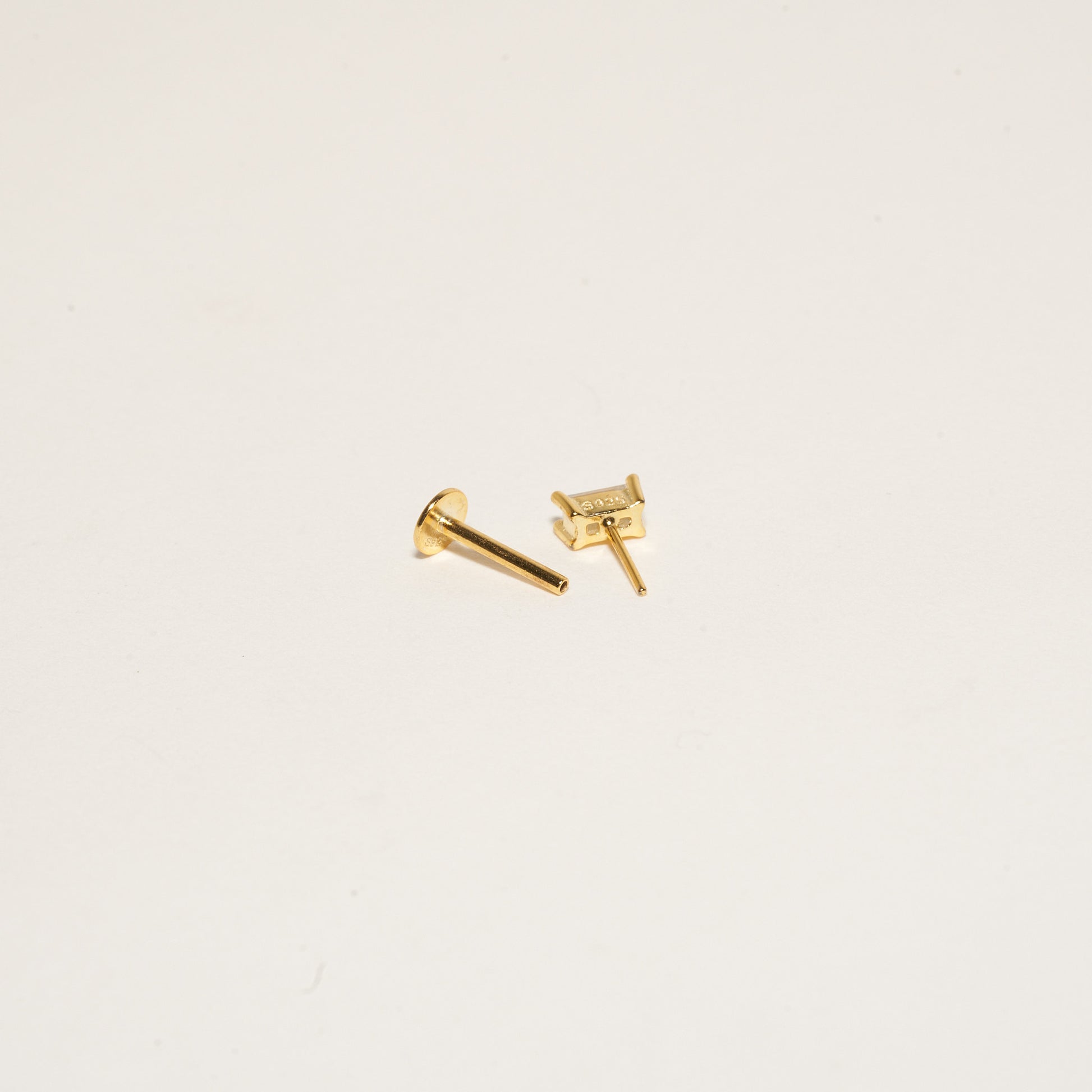 Gold stud earrings on a light beige background