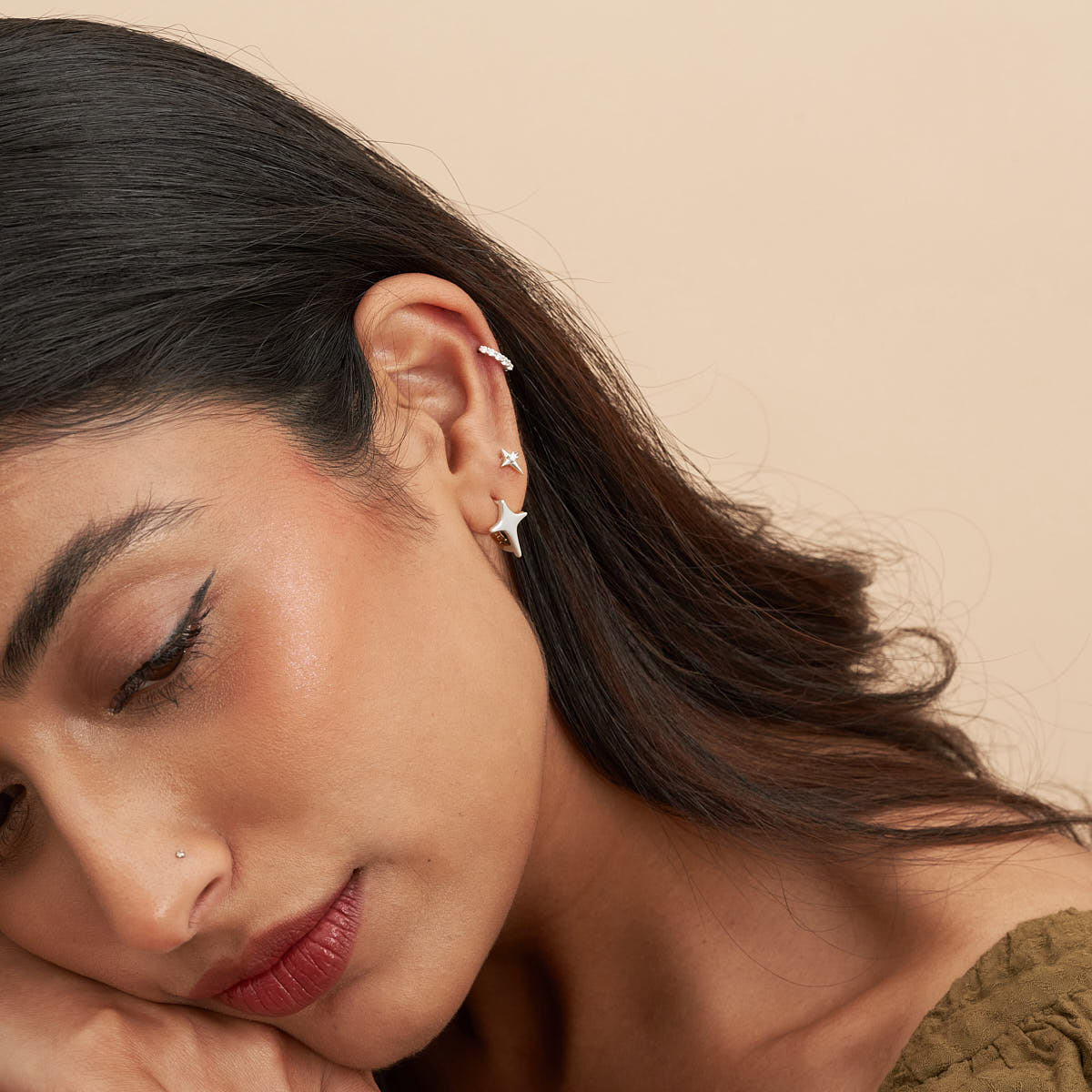 Close-up of a woman wearing star-shaped earrings with a neutral background