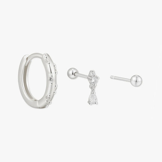 Set of silver hoop earrings and stud earrings on a white background