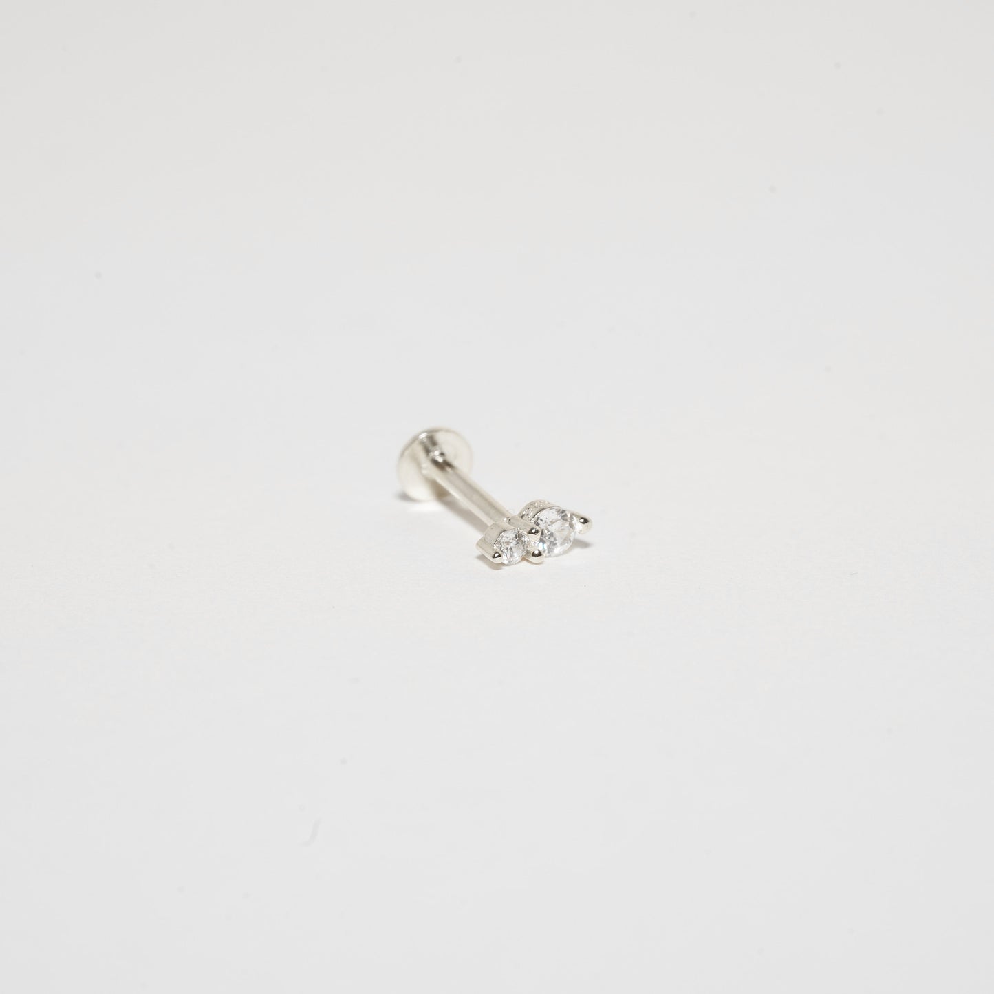 Silver earring with a small gemstone on a light gray background