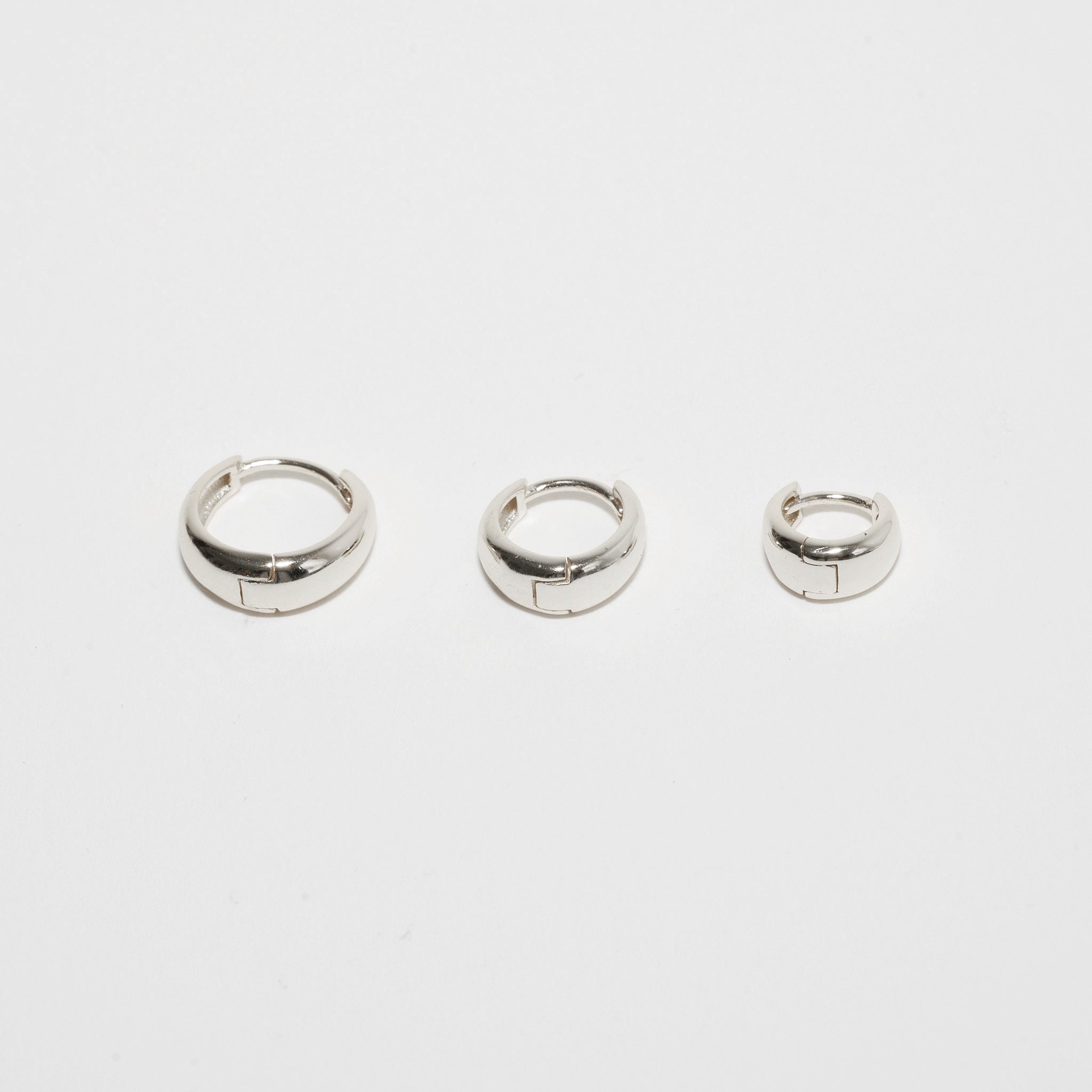 Three silver hoop earrings on a white background