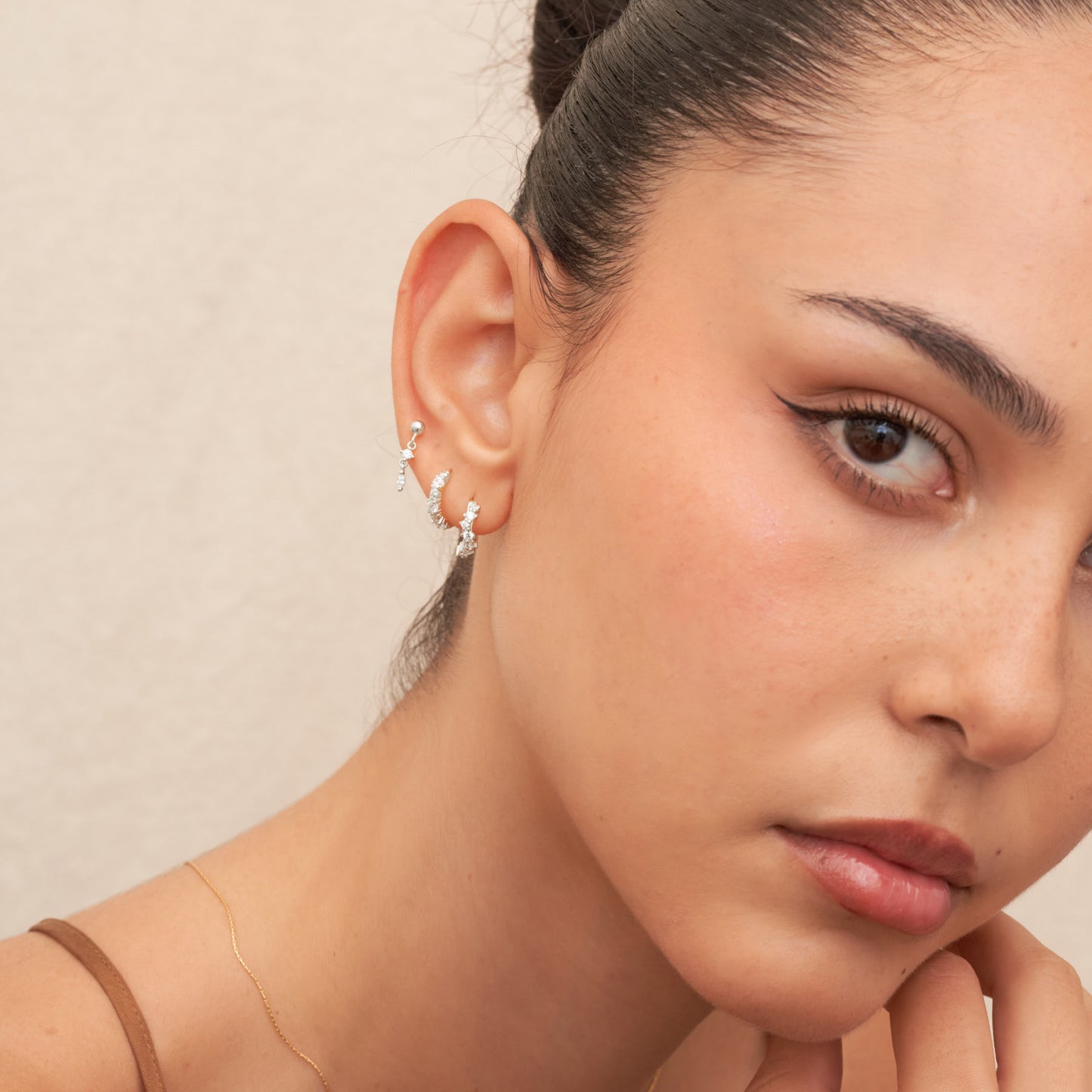 Close-up of a woman wearing a delicate earring with a neutral background