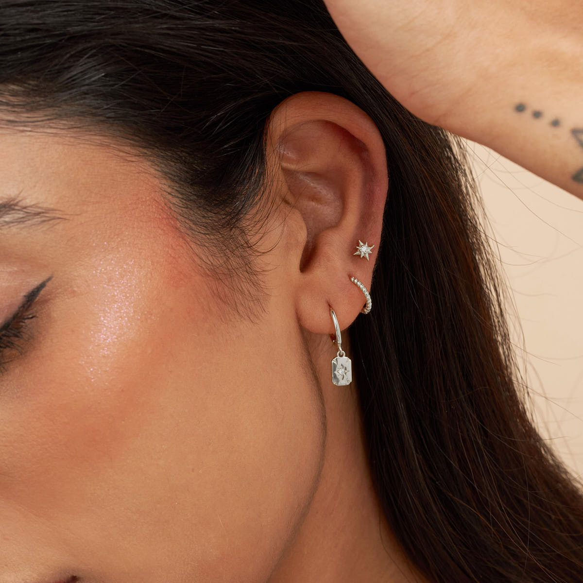 Close-up of a person wearing a diamond earring.