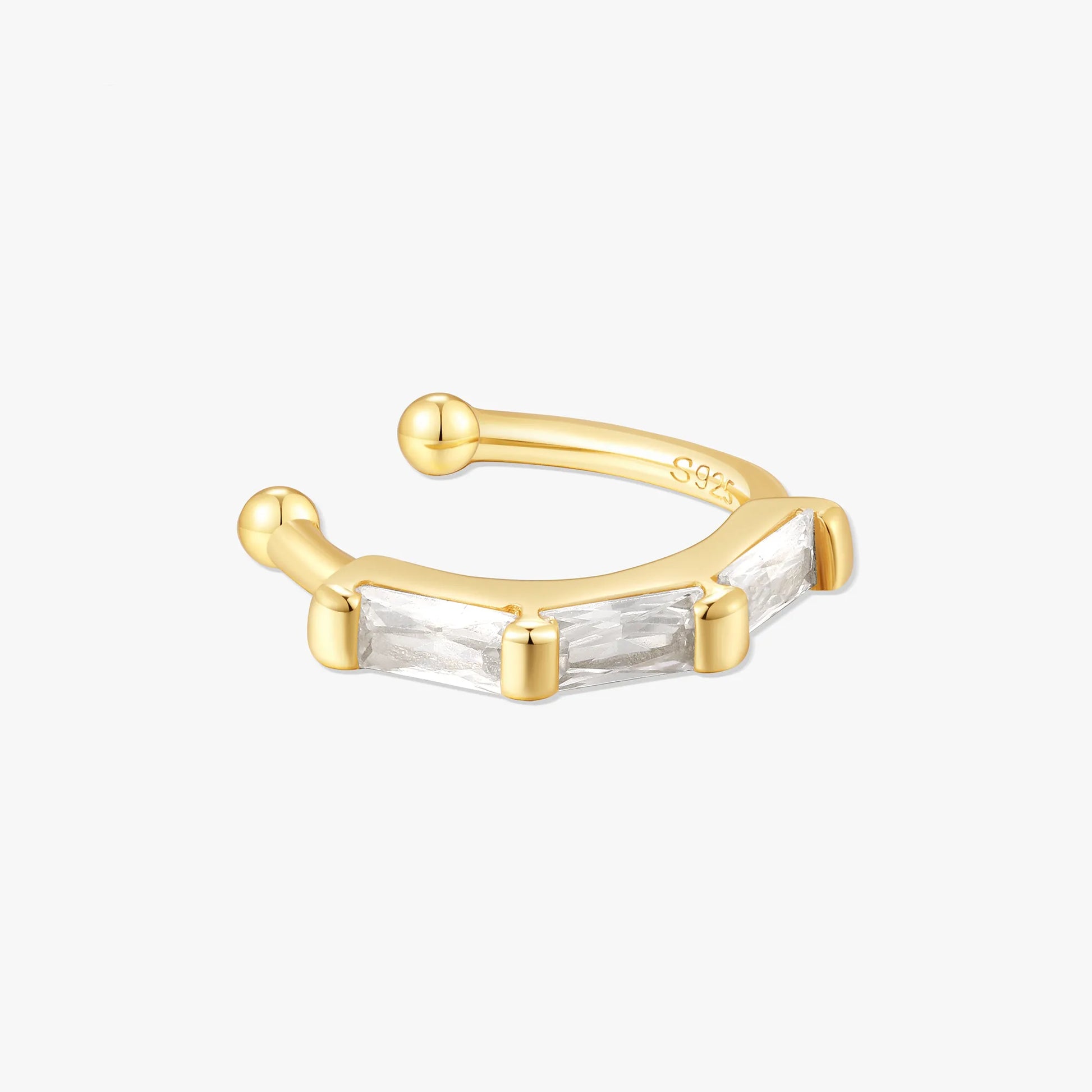 Gold ear cuff with baguette cut gemstone on a white background