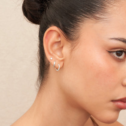 Close-up of a woman's ear wearing two hoop earrings against a neutral background