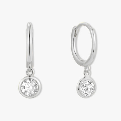 Pair of silver hoop earrings with round clear gemstones on a white background