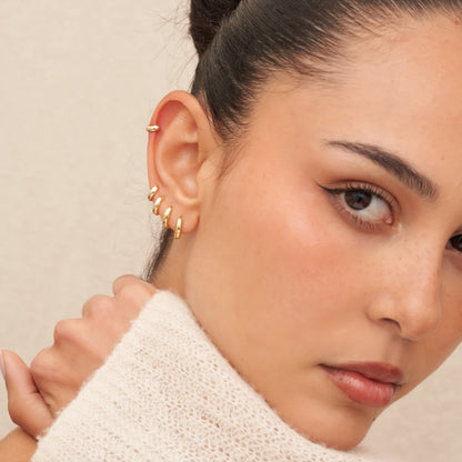 Close-up of a woman wearing gold earrings with a neutral background