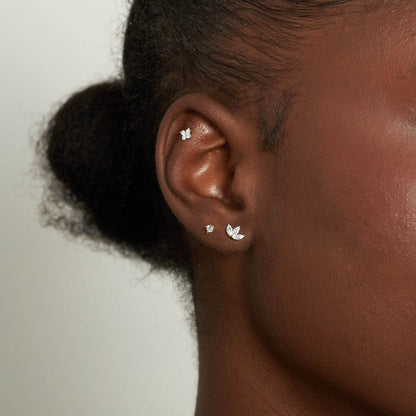Close-up of an ear wearing gold earrings with a neutral background
