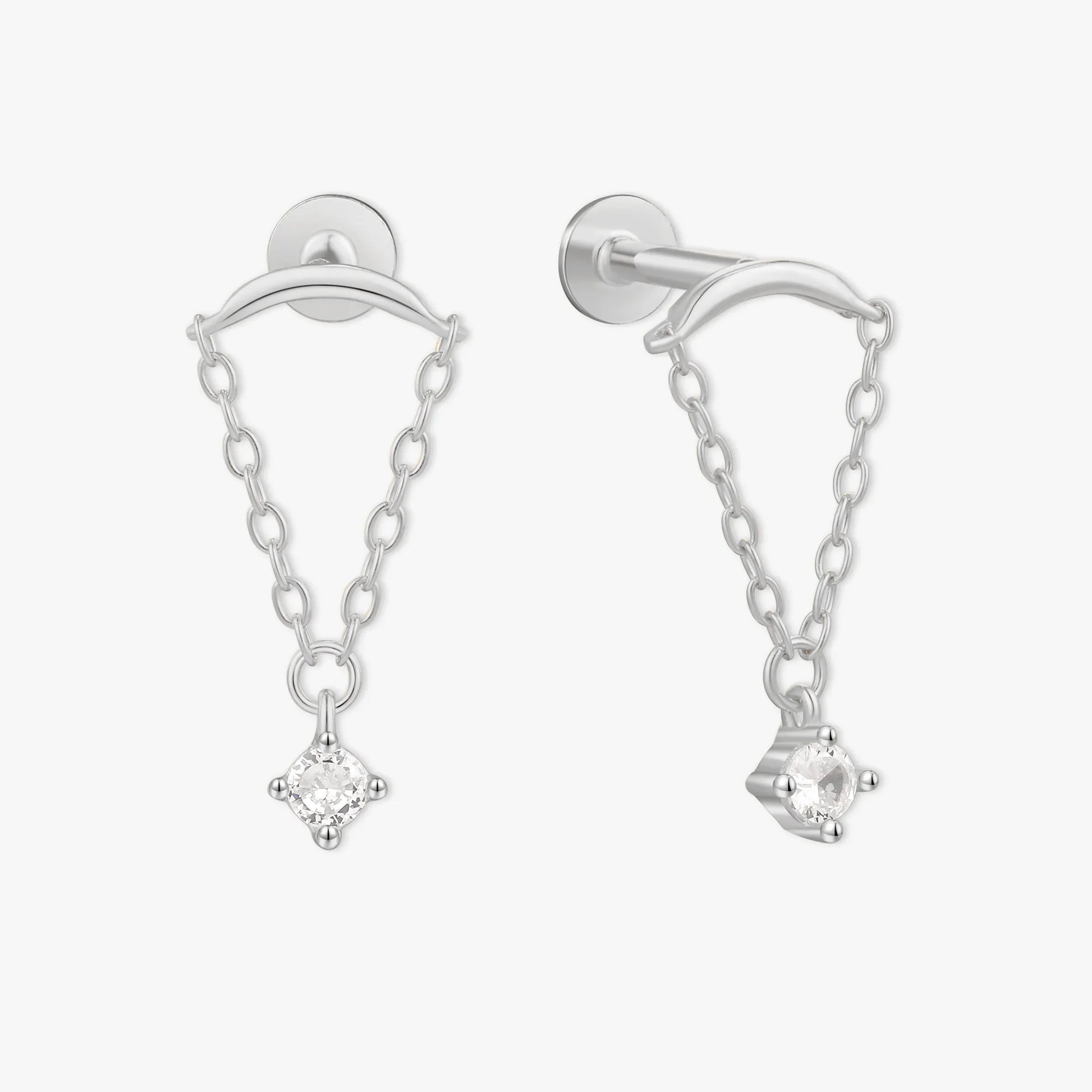 Silver earrings with chain and clear gemstones on a white background