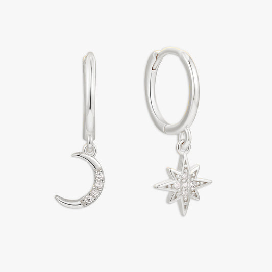 Silver hoop earrings with moon and star charms on a white background