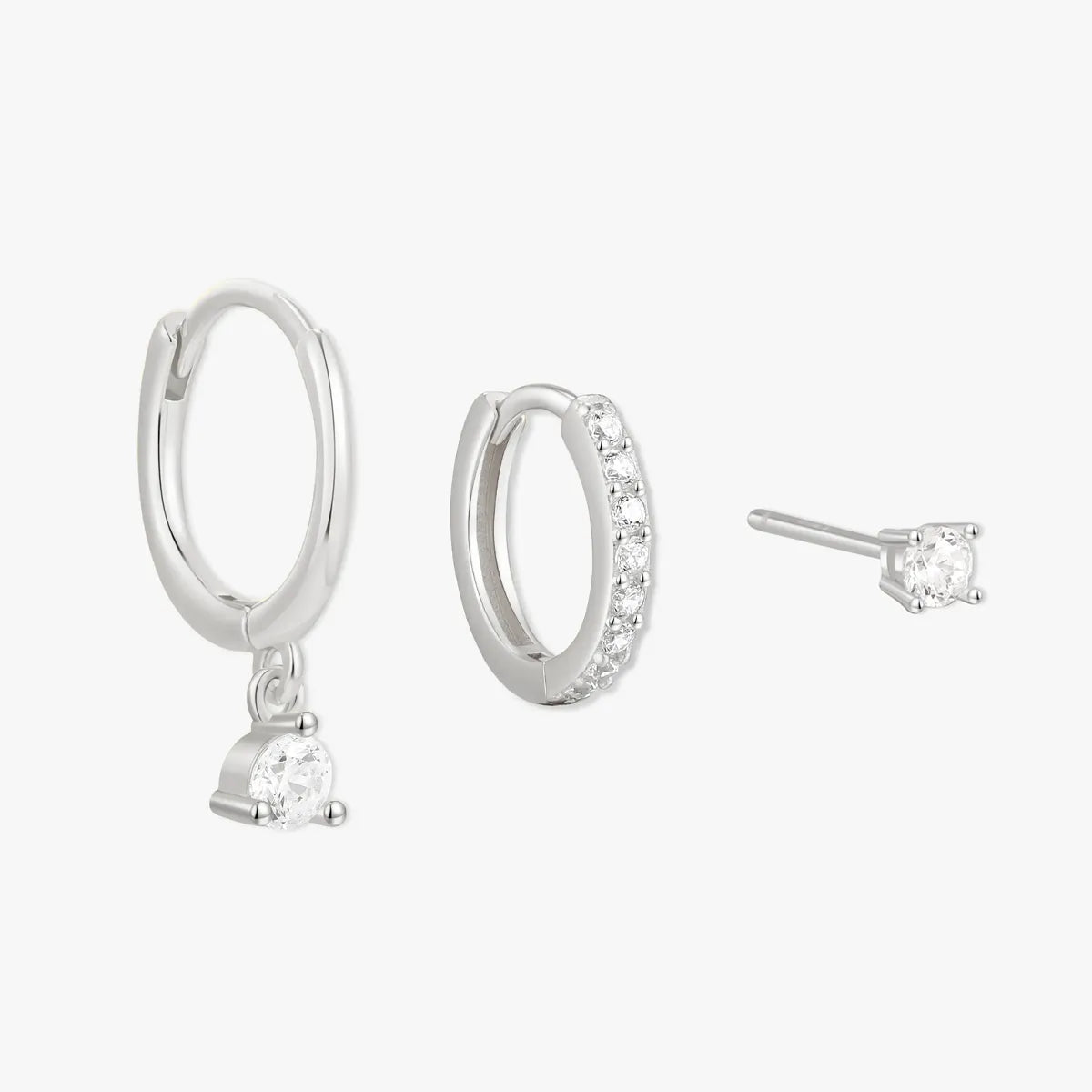 Set of silver hoop earrings and a single stud earring on a white background