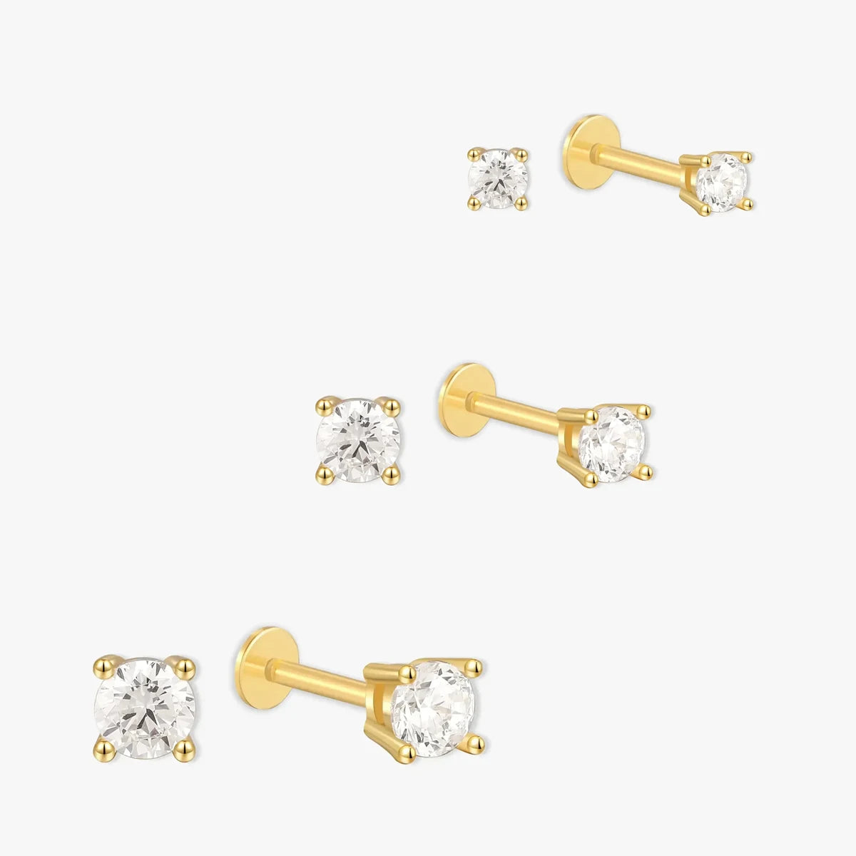 Set of gold stud earrings with clear gemstones on a white background