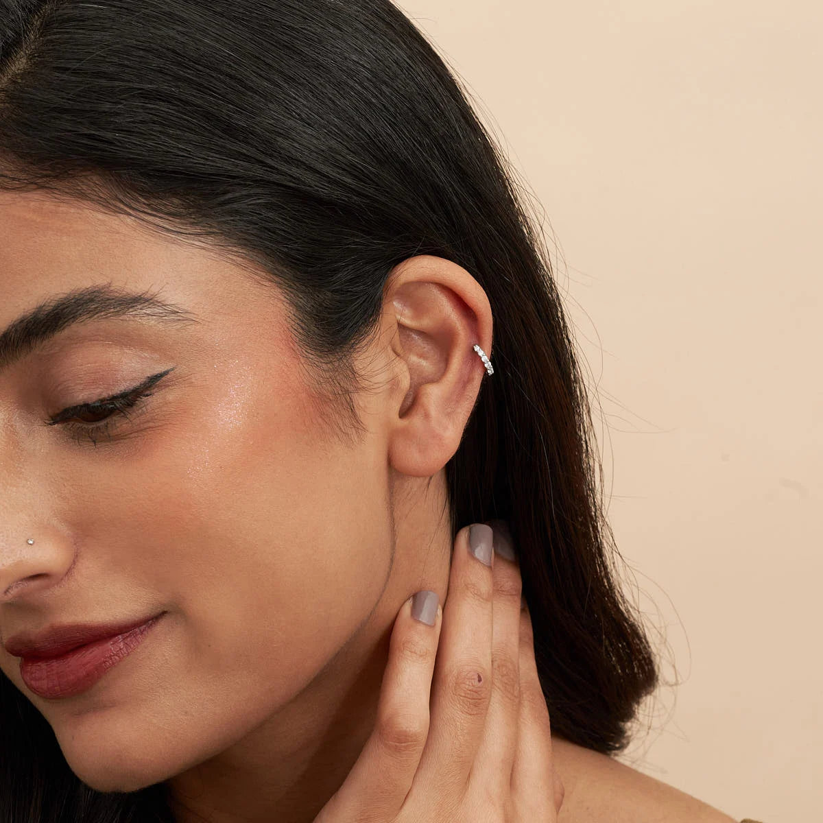 Close-up of a woman wearing a diamond earring on a beige background