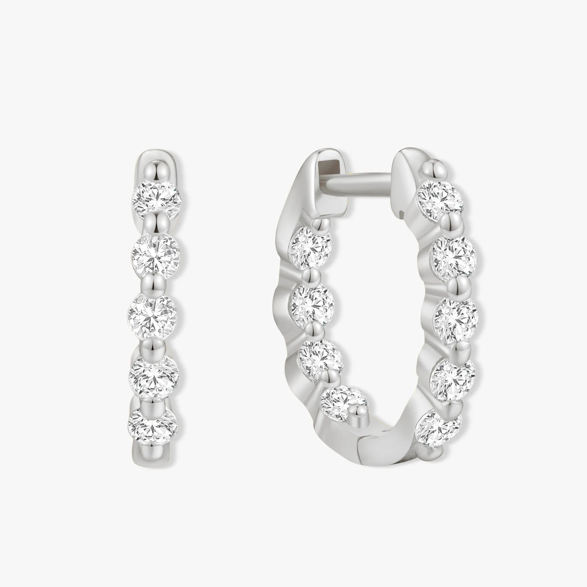 Silver hoop earrings with clear gemstones on a white background
