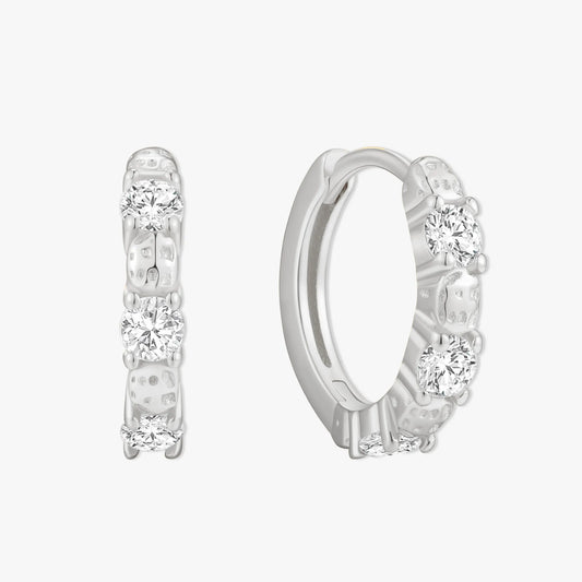Silver hoop earrings with clear gemstones on a white background