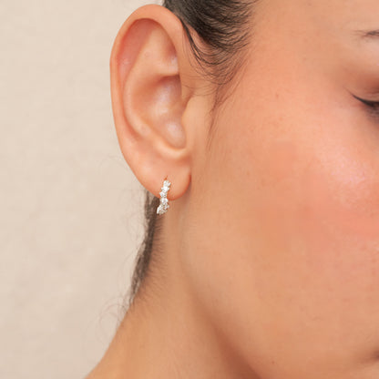 Close-up of an ear wearing a silver earring with a neutral background