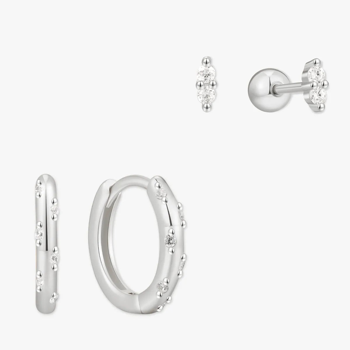 Set of silver hoop earrings and stud earrings on a white background