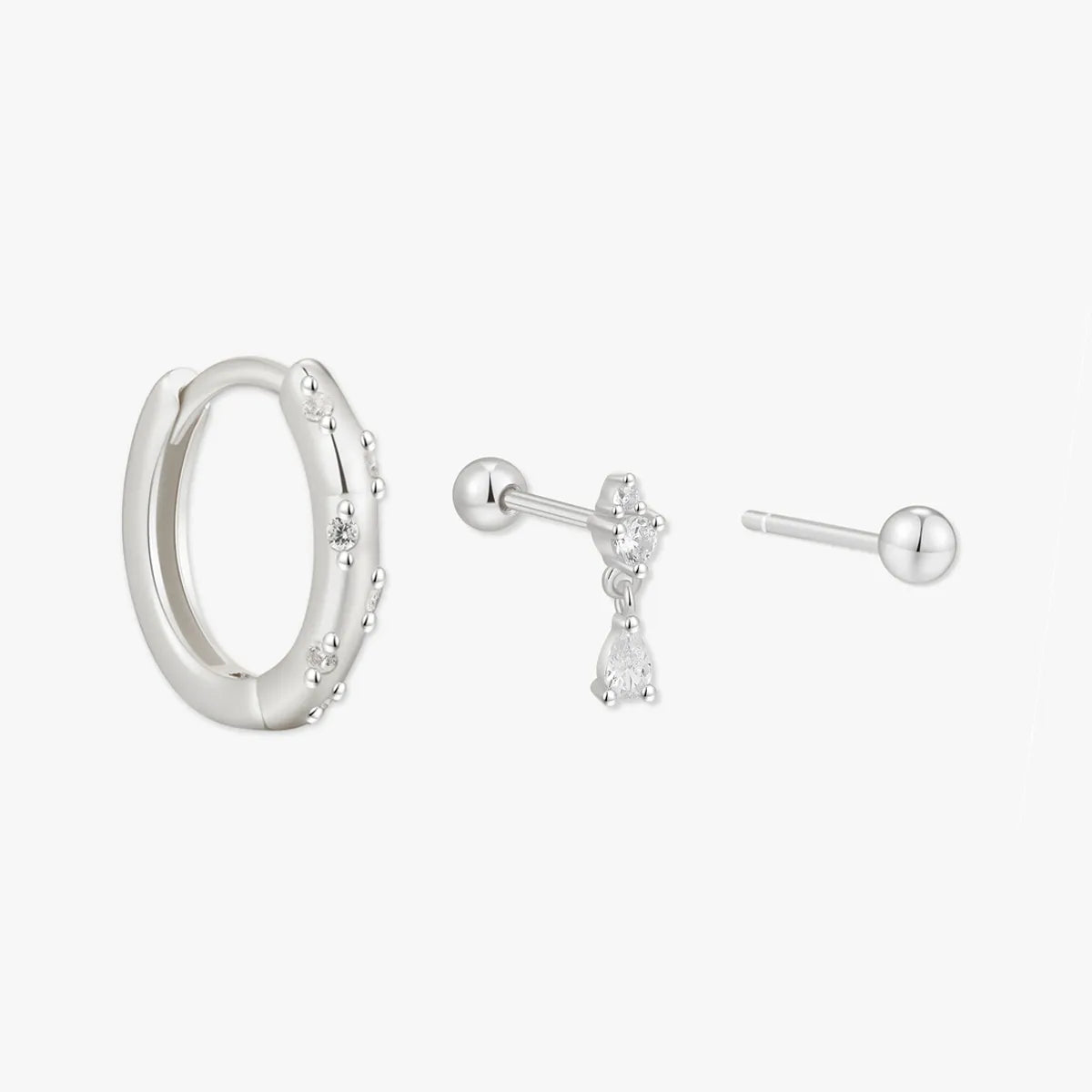 Set of silver hoop earrings and stud earrings on a white background