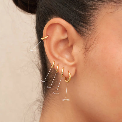 Gold hoop earrings displayed on an ear with size labels.