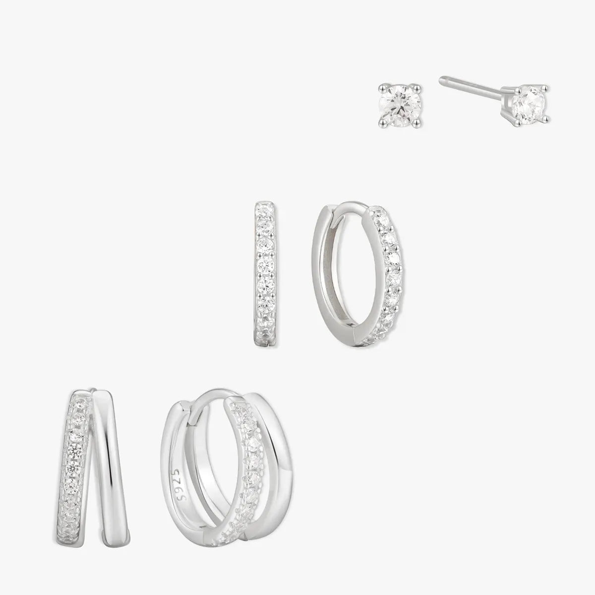 Set of silver hoop earrings and stud earrings on a white background