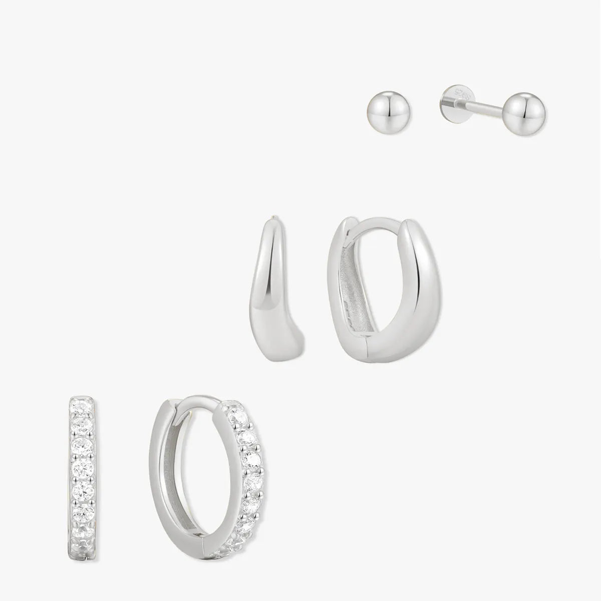 Set of silver hoop earrings and a stud on a white background