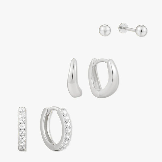 Set of silver hoop earrings and a stud on a white background