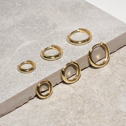 Set of gold hoop earrings on a textured surface