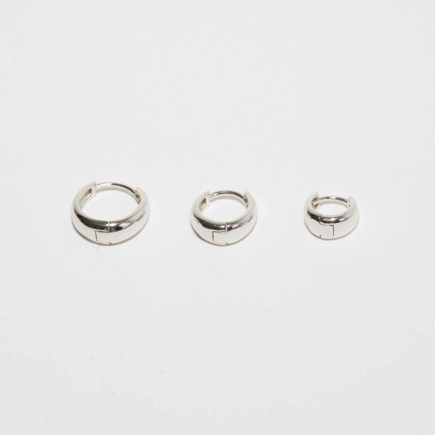 Three silver hoop earrings on a white background
