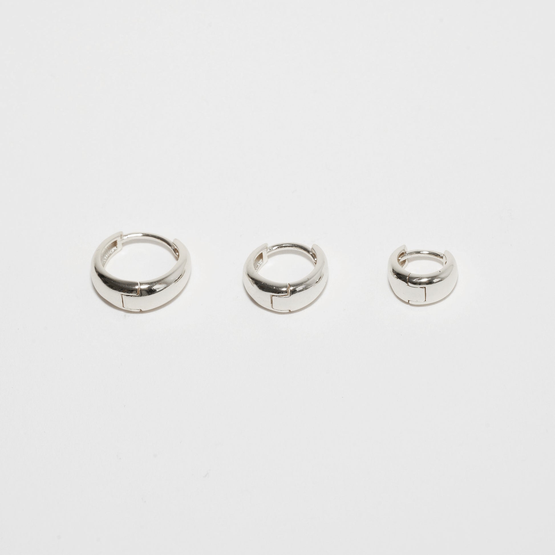 Three silver hoop earrings on a white background
