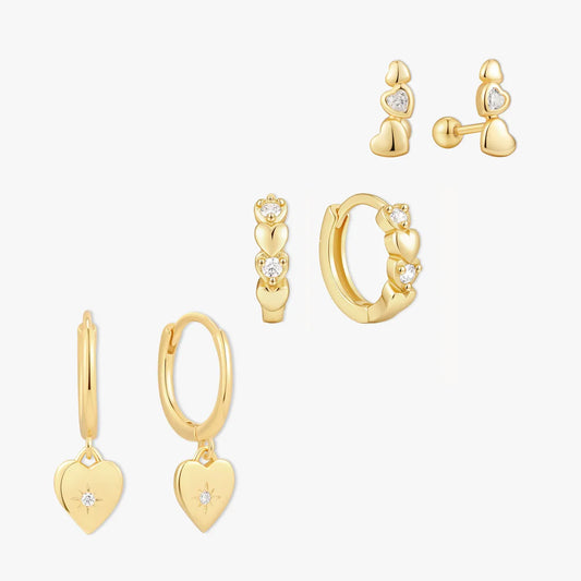 Set of gold hoop earrings with heart designs on a white background