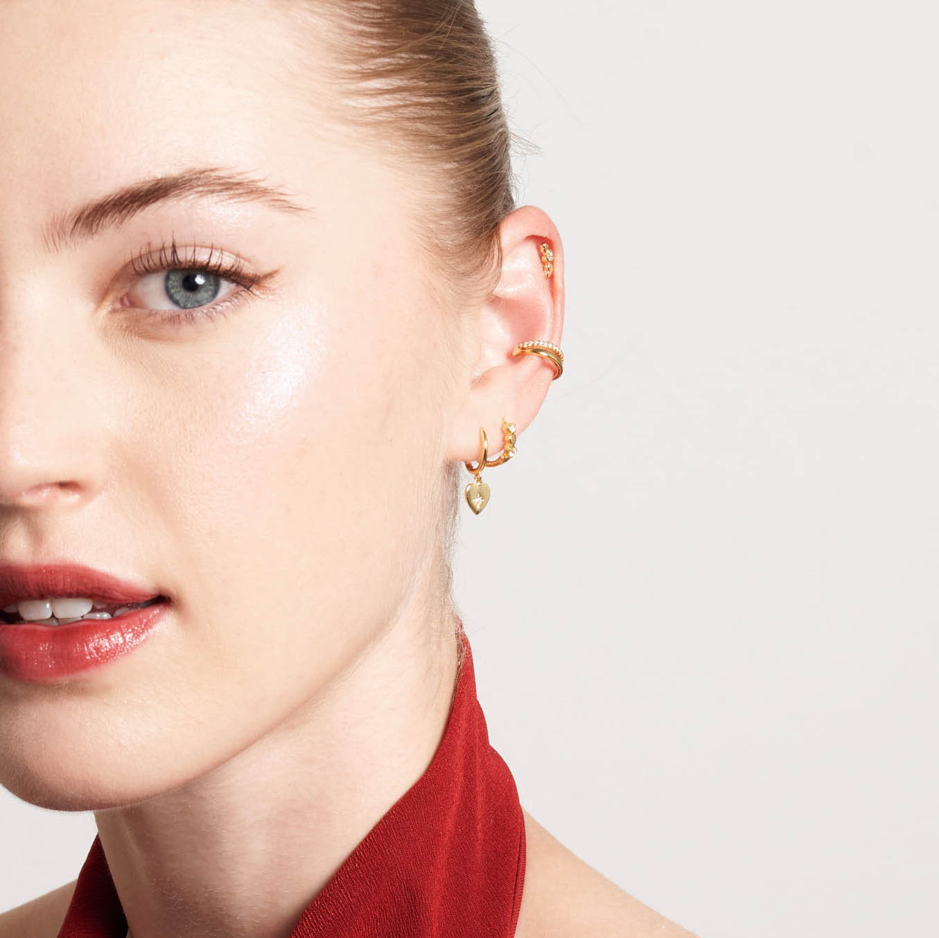 Close-up of a woman wearing gold earrings with a plain background