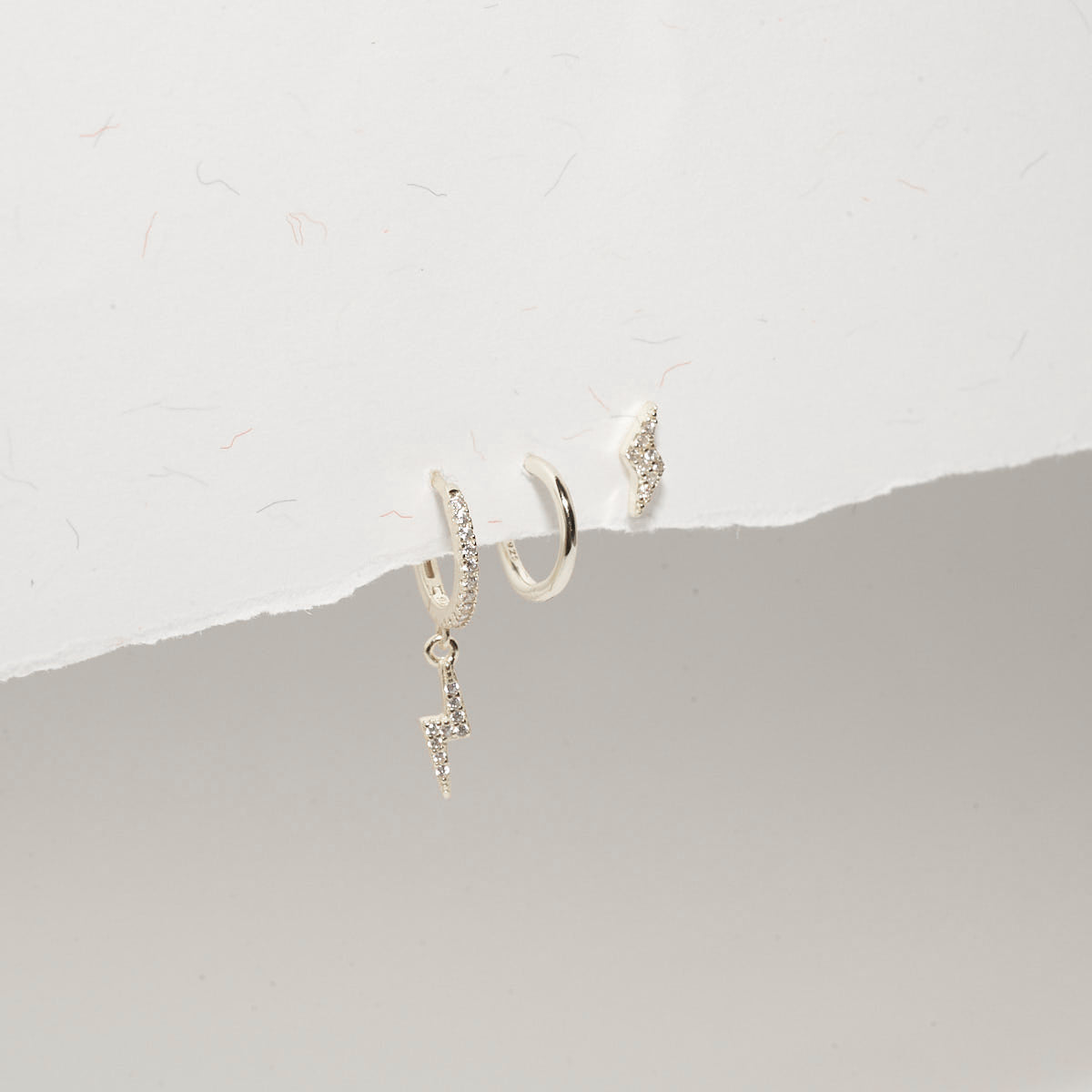 Silver hoop earrings with small decorative elements on a light gray background