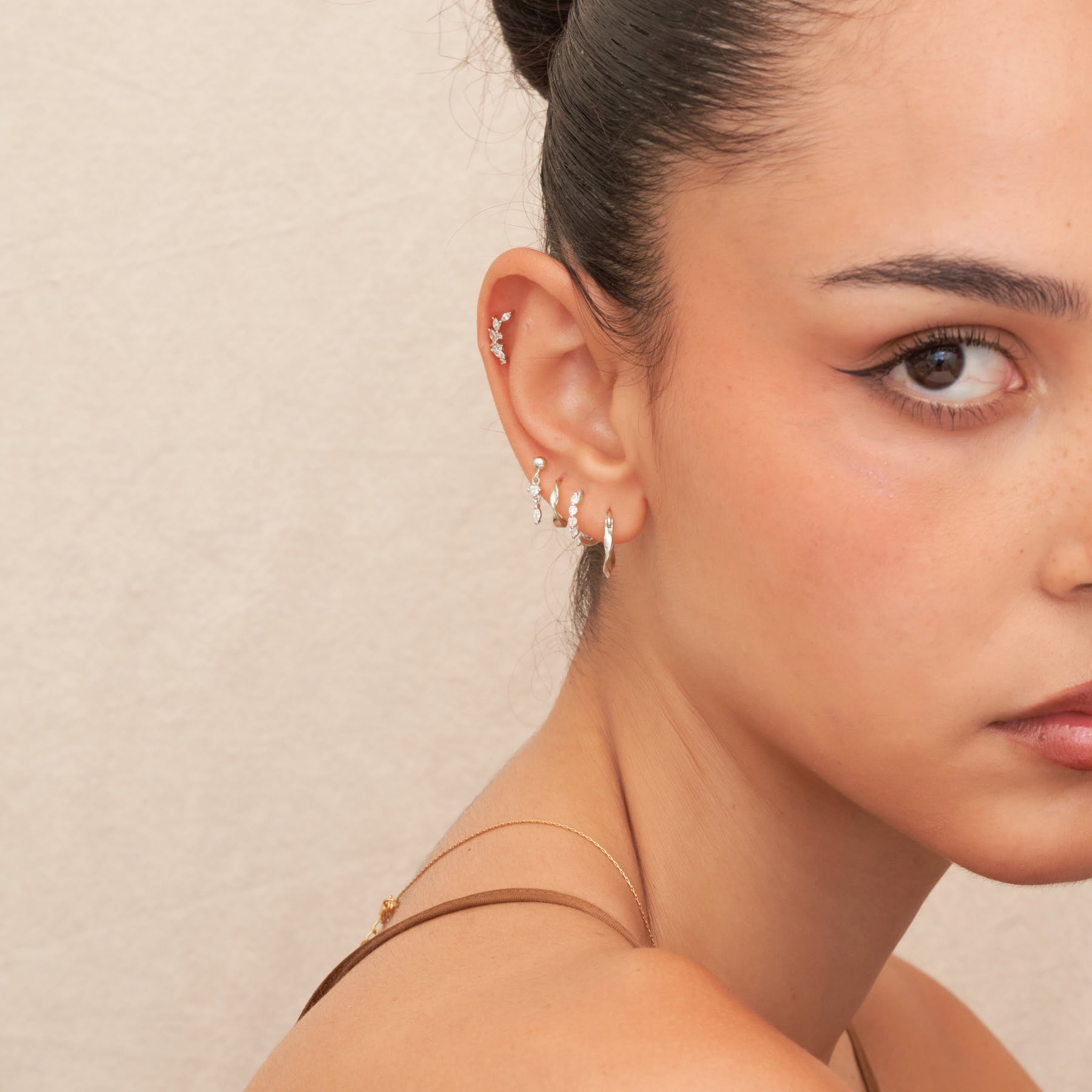 Close-up of a woman's ear with earrings against a neutral background