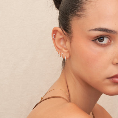 Close-up of a woman's ear with earrings against a neutral background