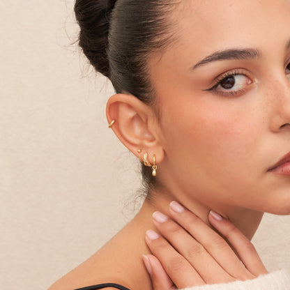 Close-up of a woman wearing gold earrings with a neutral background