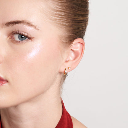 Close-up of a woman wearing gold earrings with a plain background