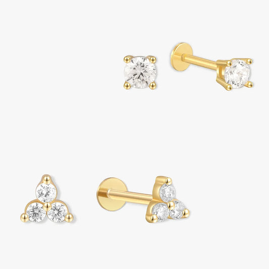 Set of gold earrings with clear gemstones on a white background