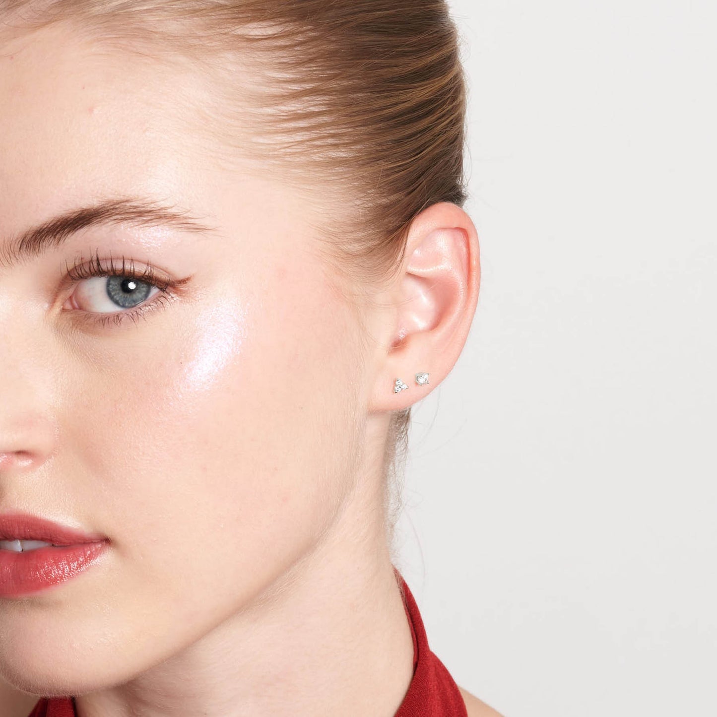 Close-up of a woman wearing small stud earrings on a plain background
