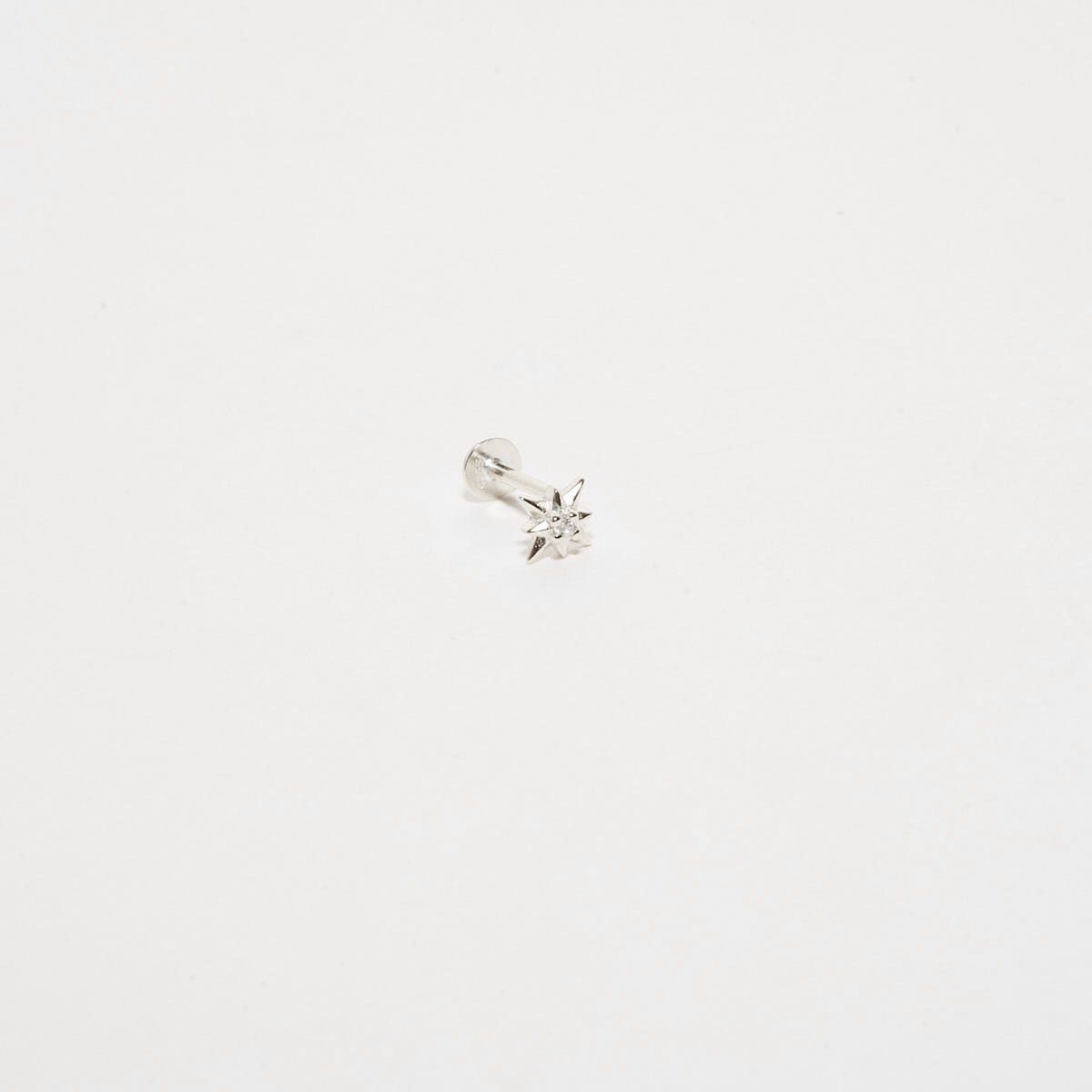 Silver earring with a small gemstone on a light gray background