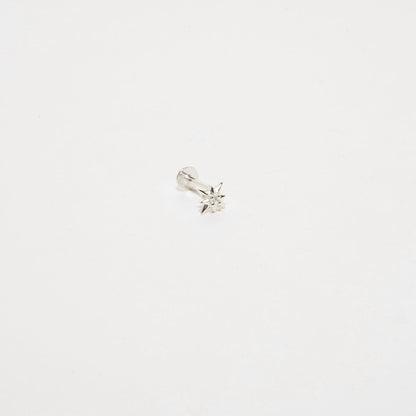 Silver earring with a small gemstone on a light gray background