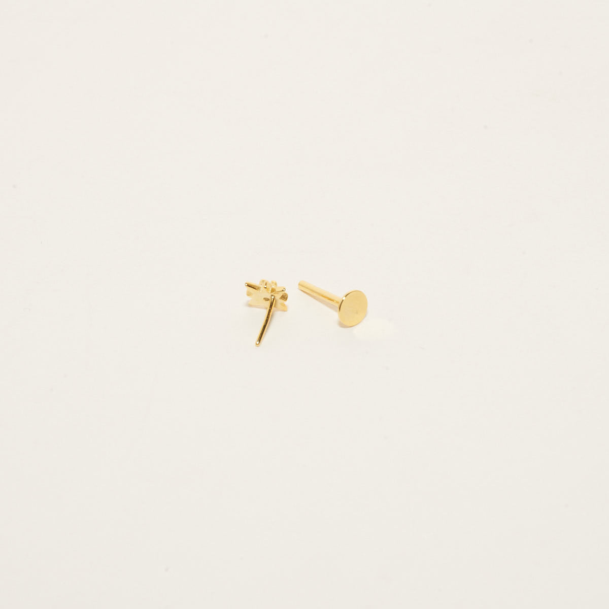 Gold stud earrings on a light beige background