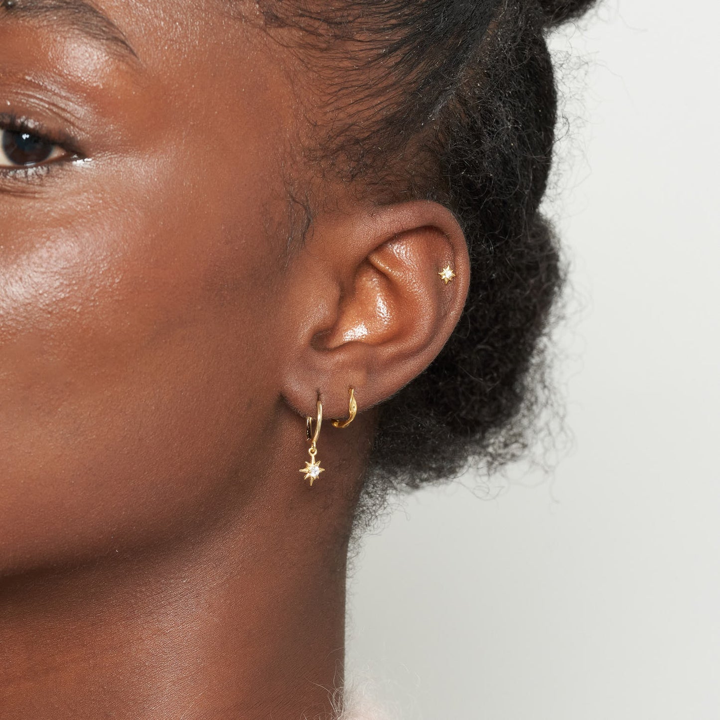 Close-up of a person wearing earrings with a neutral background