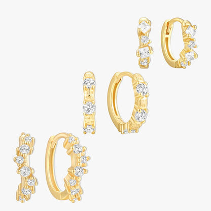 Set of gold hoop earrings with clear gemstones on a white background