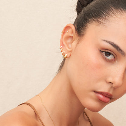 Close-up of a woman's face with gold earrings against a beige background