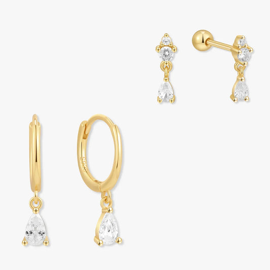 Set of gold earrings with clear gemstones on a white background