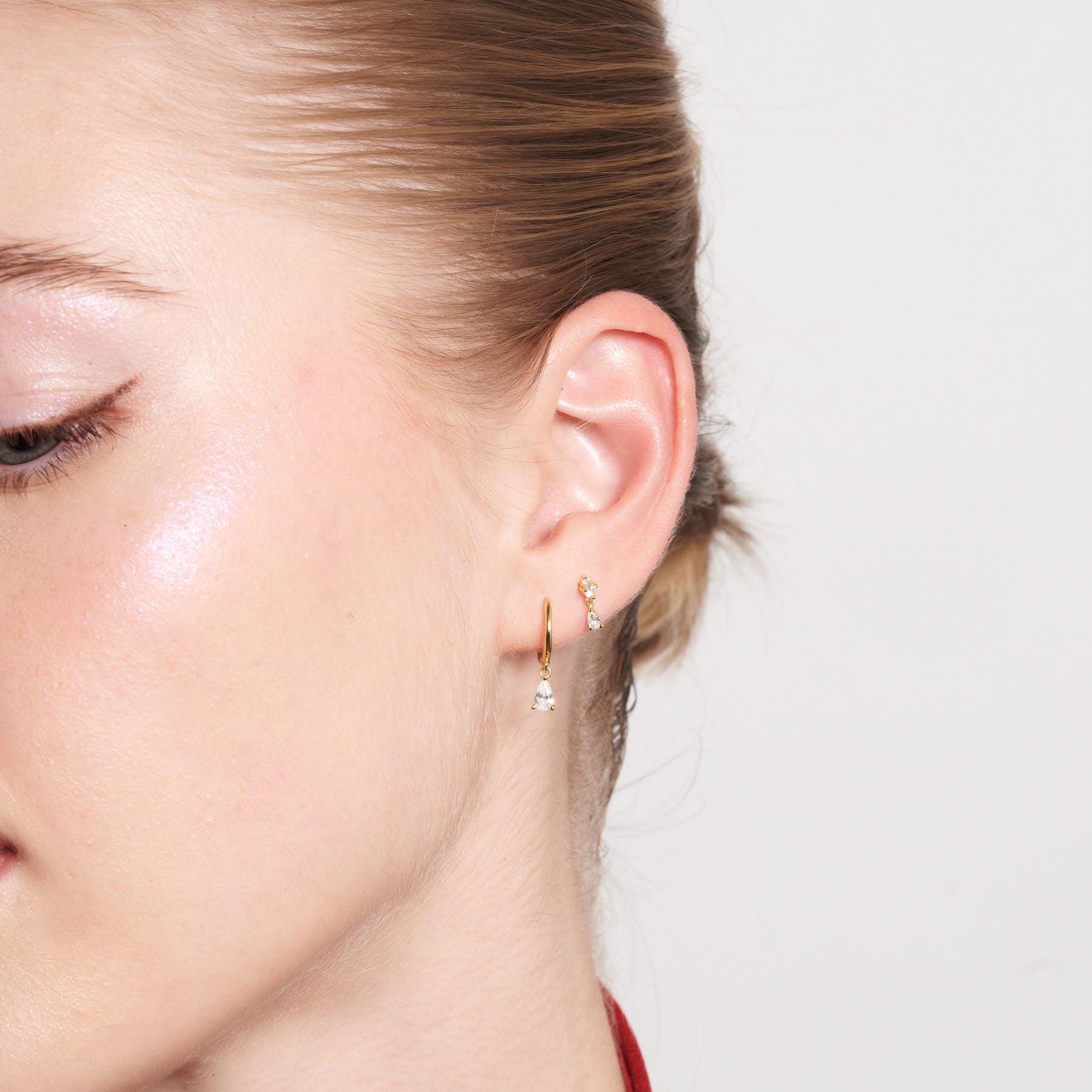 Close-up of a person wearing gold earrings with a blurred background
