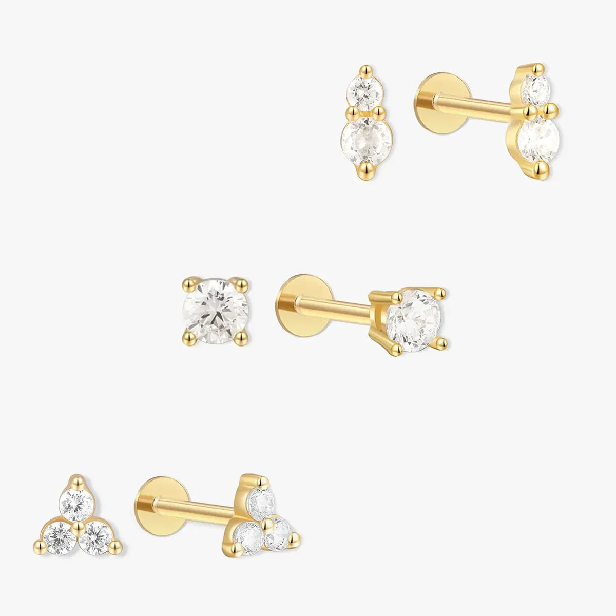 Set of gold earrings with clear gemstones on a white background