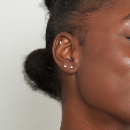 Close-up of a person's ear with earrings against a neutral background