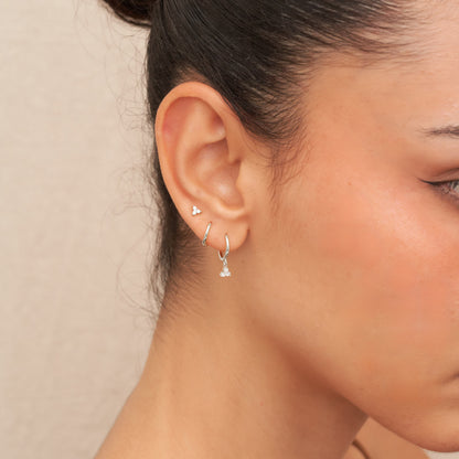 Close-up of a person wearing silver earrings with a neutral background